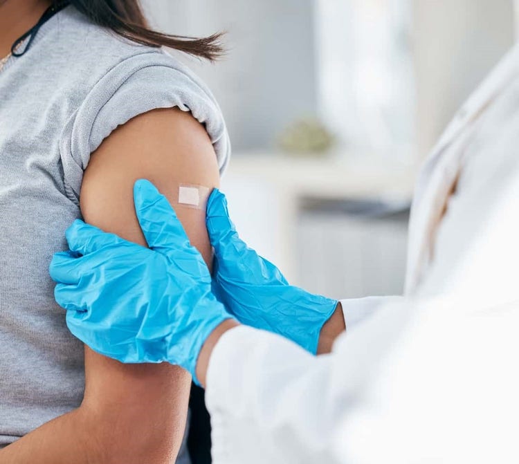 Vaccine provider putting a bandaid on a newly vaccinated patient