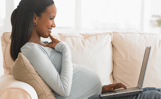 Actor portrayal of a pregnant woman looking at a laptop