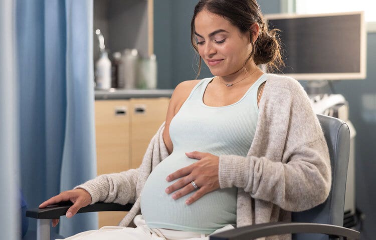 Actor portrayal of a pregnant woman feeling her belly