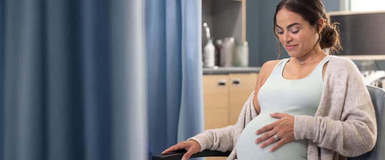 Actor portrayal of a pregnant woman feeling her belly