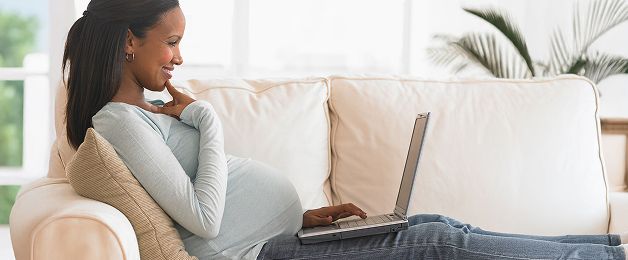 Actor portrayal of a pregnant woman looking at a laptop